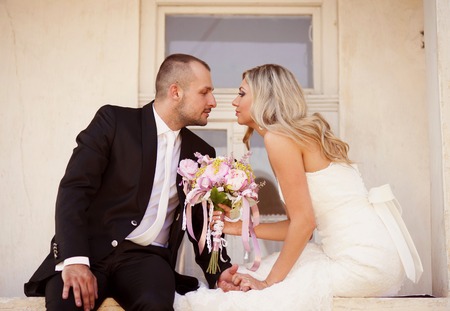 Happy bride and groom posing by the old houseの写真素材