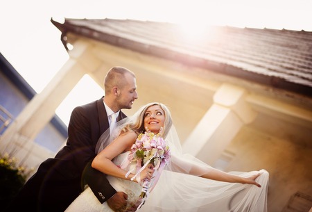 Happy bride and groom posing by the old houseの写真素材