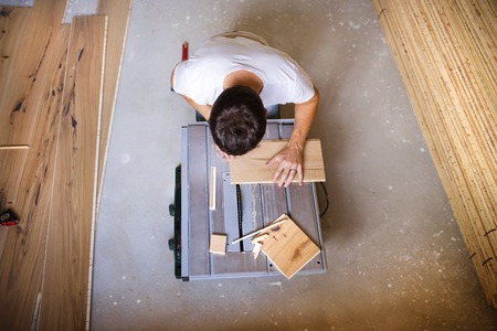 High angle view of handyman cutting plywood on circular saw in the new houseの写真素材