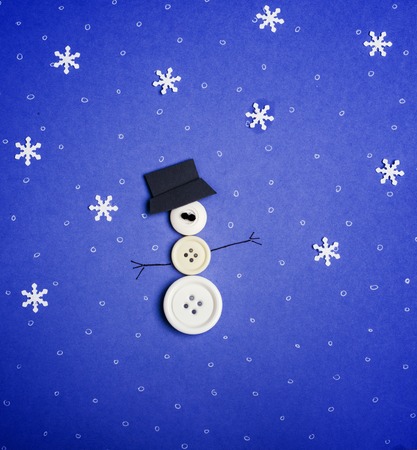 Winter background. Snowman made from buttons and snowflakes on blue backgroundの写真素材