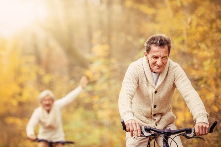 Active seniors ridding bike in autumn nature. They having fun outdoor.の写真素材