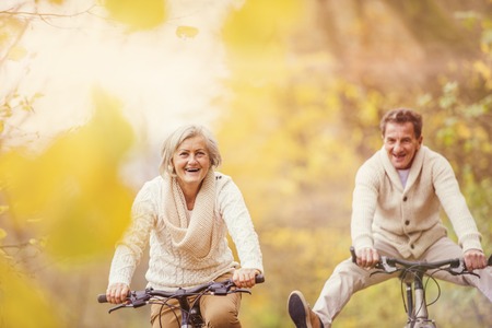 Active seniors ridding bike in autumn nature. They having fun outdoor.の写真素材