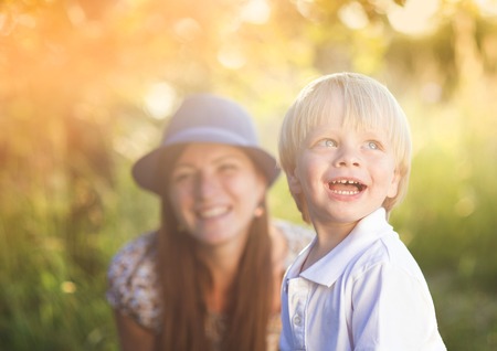 Mother and little son enjoying sunshine outside in natureの写真素材