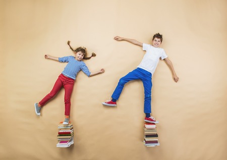 Happy children playing with group of books in studioの写真素材