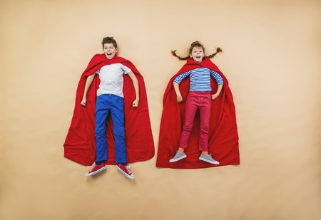 Children are playing as superheroes with red coatsの写真素材