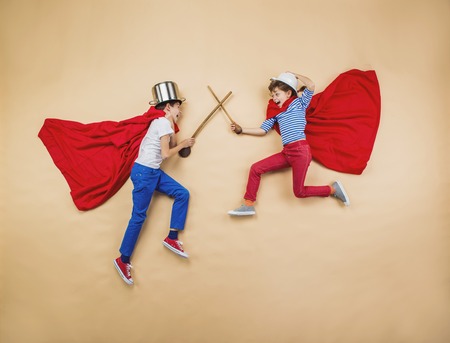 Children are playing as superheroes with red coatsの写真素材