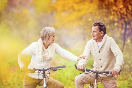 Active seniors riding bike in autumn nature. They relax outdoor.の写真素材