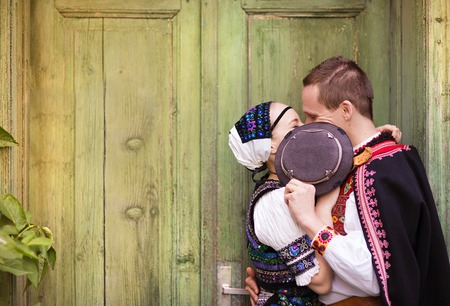Love couple standing by the door wearing national Eastern Europe folk costumes.の写真素材