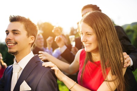 Full length portrait of wedding guests dancing and having fun at the wedding garden party in a green sunny parkの写真素材