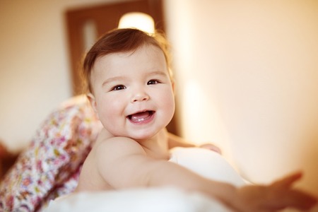 Cute little baby playing and having fun on a sofaの写真素材