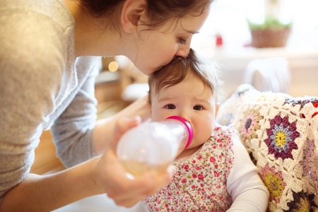 Young mother and her little daughter having breakfast togetherの写真素材