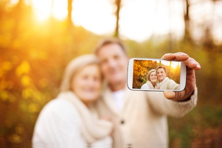 Active seniors taking selfies of them having fun outside in the autumn forestの写真素材
