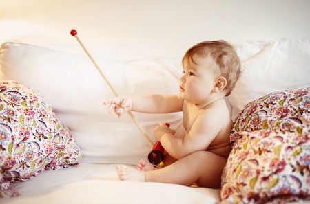 Cute little baby playing and having fun on a sofaの写真素材