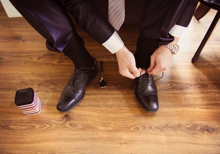 Young groom putting on shoes and getting ready for wedding.の写真素材