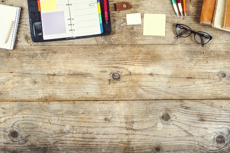 Mix of office supplies on a wooden table background. View from above.