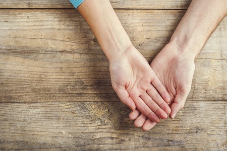 Hands of man and woman holding together. Studio shot on a wooden background, view from above.の写真素材