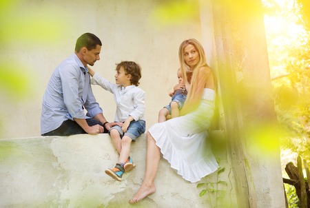 Happy young family spending time together sitting outside on a porch of old house.の写真素材