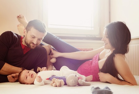 Happy young parents with their little baby girl at homeの写真素材