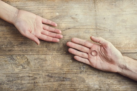 Man offering a wedding ring tenderly to a woman. Studio shot on a wooden background, view from above.の写真素材