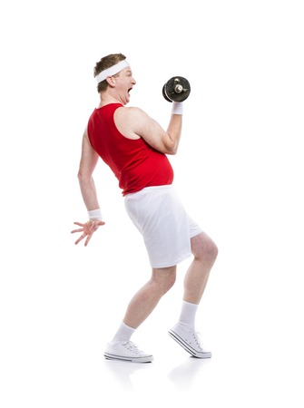 Funny weak body builder tries to lift a weight. Studio shot on white background.の写真素材