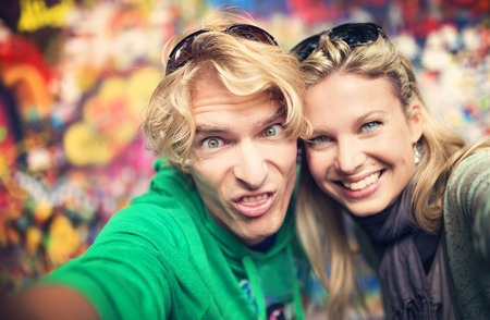Beautiful young couple taking selfie of themselves as they make funny facesの写真素材