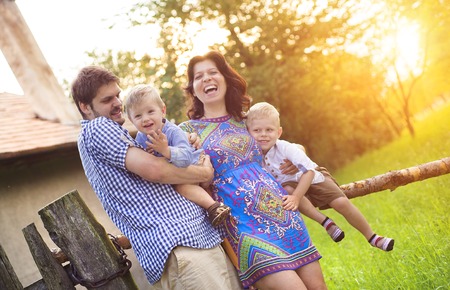 Happy young family spending time together and having fun in front of an old countryside house.の写真素材