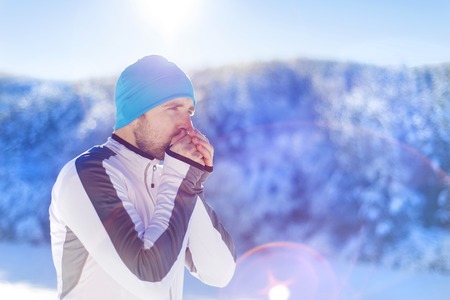 Young runner warms him up while resting during his training outside in sunny winter parkの写真素材