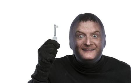 Thief in balaclava making funny faces, dressed in black. Studio shot on white background.の写真素材