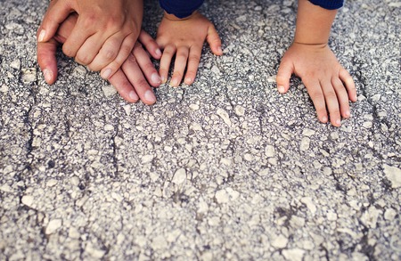 Hands of parents with their kids laid on the groundの写真素材