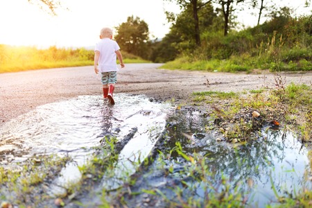 Little boy playing outside in a puddleの写真素材