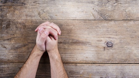 Hands of praying young man on a wooden desk background.の素材 [FY31037086006]