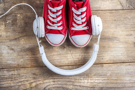 Concept with red sneakers and tablet with white headphones laid on wooden floor background.の写真素材