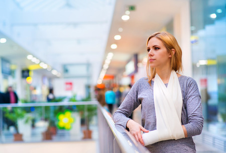 Beautiful woman with broken arm inside of a shopping centerの写真素材