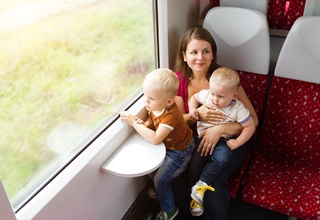 Mother with sons in her lap traveling in train.の写真素材