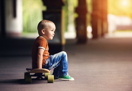Cute little boy with his skateboard on a walk in the cityの写真素材