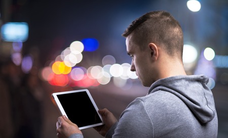 Young sportsman in the night city with a tabletの写真素材