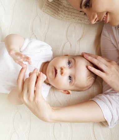 Cute little baby girl and her mother lying on a knitted blanket.の写真素材