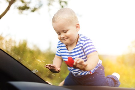 Little boy playing on a windshield of a carの写真素材
