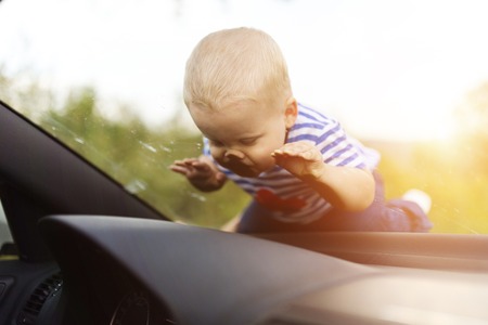 Little boy playing on a windshield of a carの写真素材