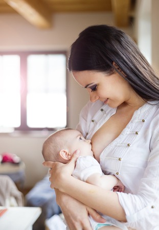 Mother breastfeeding her little baby girl in her arms.