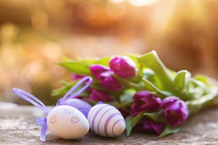 Colorful easter eggs and beautiful spring flowers laid on a floor.