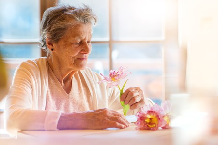 Beautiful senior woman holding a pink flower.