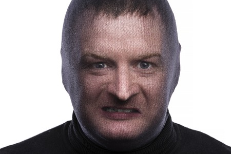 Thief in balaclava making funny faces, dressed in black. Studio shot on white background.の写真素材
