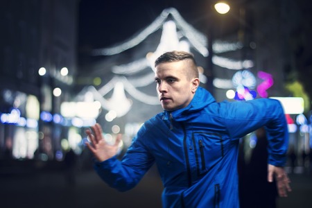 Young sportsman jogging in the night cityの写真素材