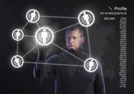 Thief in action stealing information with balaclava on his face, dressed in black. Studio shot on black background.の写真素材