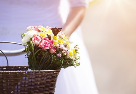 Unrecognizable beautiful young bride outside on a bike at the sunsetの写真素材