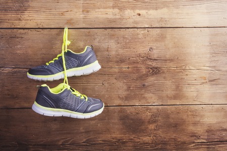 Pair of sneakers hang on a nail on a wooden fence backgroundの写真素材