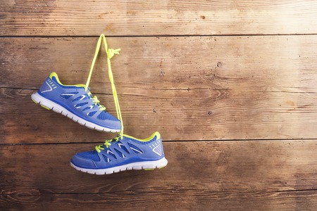 Pair of sneakers hang on a nail on a wooden fence backgroundの写真素材