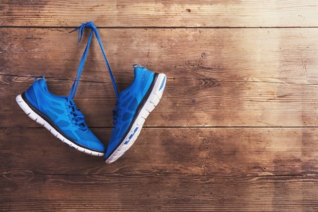 Pair of sneakers hang on a nail on a wooden fence background
