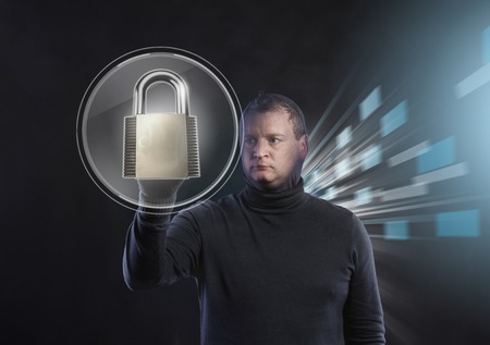 Thief in action stealing information with balaclava on his face, dressed in black. Studio shot on black background.の写真素材